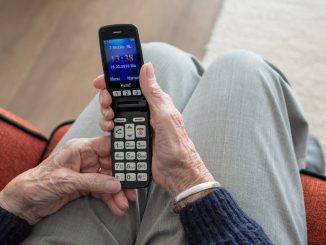 Ältere Person, die lächelnd auf ihr Smartphone schaut