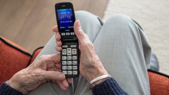 Ältere Person, die lächelnd auf ihr Smartphone schaut