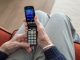 Ältere Person, die lächelnd auf ihr Smartphone schaut
