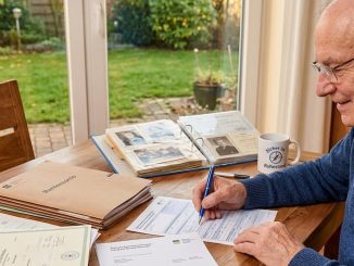 Senior sitz am Schreibtisch und füllt seinen Rentenantrag aus
