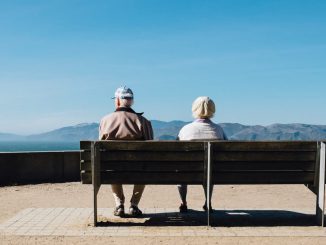 Älteres Ehepaar sitzt auf einer Bank am Meer/ Pflege auf den Kanaren Residenten