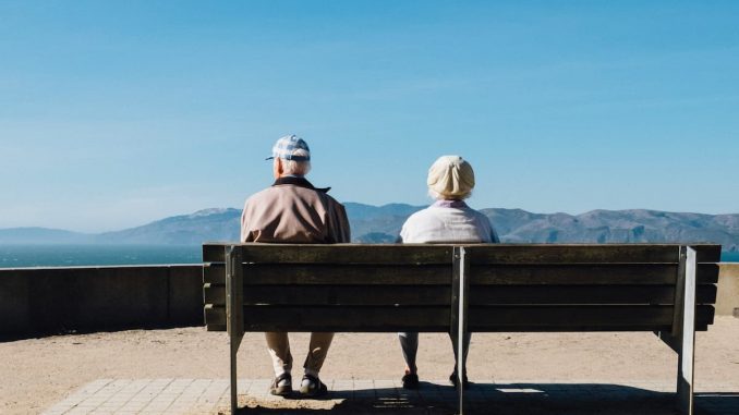 Älteres Ehepaar sitzt auf einer Bank am Meer/ Pflege auf den Kanaren Residenten