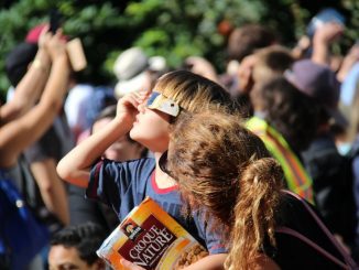 Menschen mit Schutzbrillen beobachten die Sonnenfinsternis