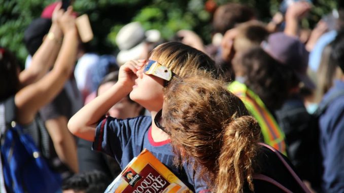 Menschen mit Schutzbrillen beobachten die Sonnenfinsternis
